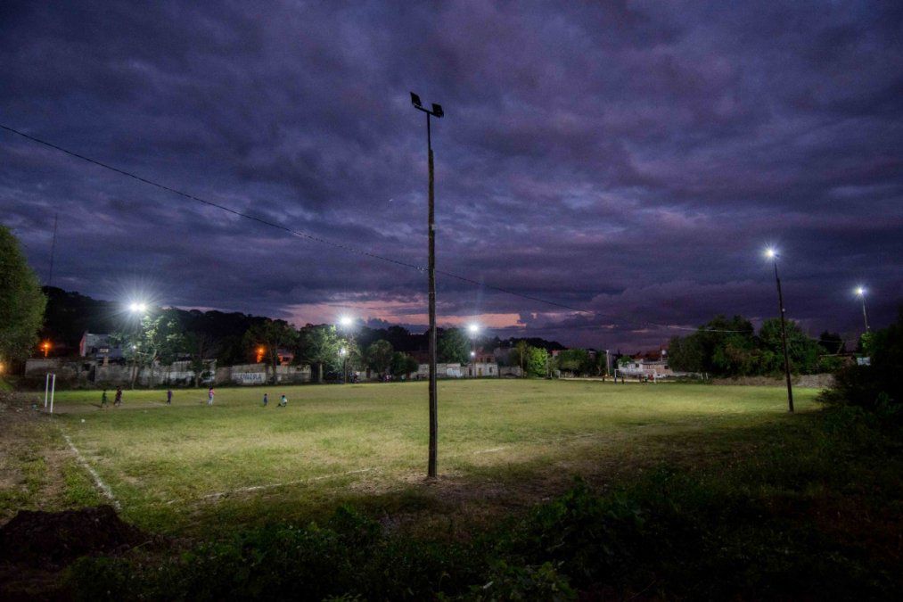 Niños jugando en el predio deportivo con sus reflectores funcionando